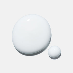 Two smooth, glossy drops of white liquid on a light background representing the texture of Cashmere Cleanse | HydroPeptide skincare product.