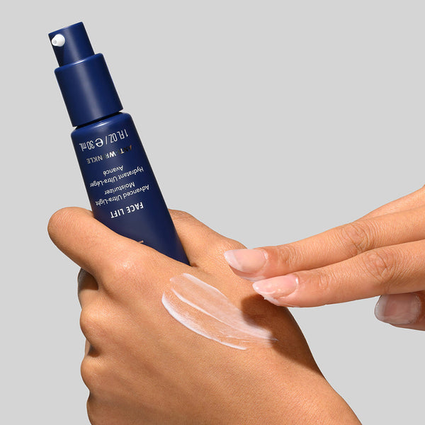 Close-up of a person applying Face Lift | HydroPeptide skincare cream from a sleek blue bottle onto the back of their hand, showcasing smooth texture and hydration benefits.