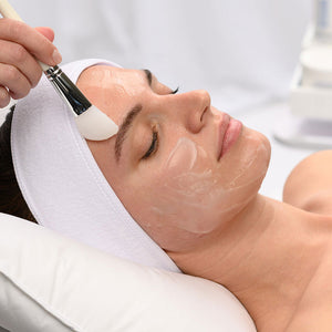 Woman receiving a gentle facial treatment with a soft brush applying a clear skincare mask while wearing the Hydro-Lock Sleep Mask | HydroPeptide for enhanced skin hydration and wellness.
