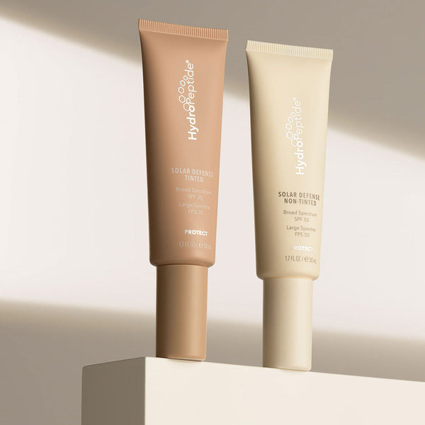 Tube of Solar Defense Non-Tinted SPF50 | HydroPeptide skincare product displayed alongside a tinted version, both designed for sun protection and wellness.