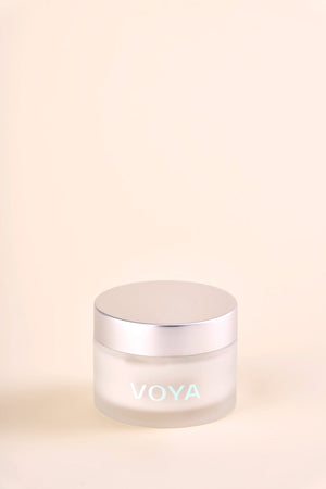 Minimalist frosted glass jar with silver lid featuring VOYA logo, containing Hydraveil Hydrating Face Mask | VOYA, set against a soft beige background, ideal for skincare and wellness.