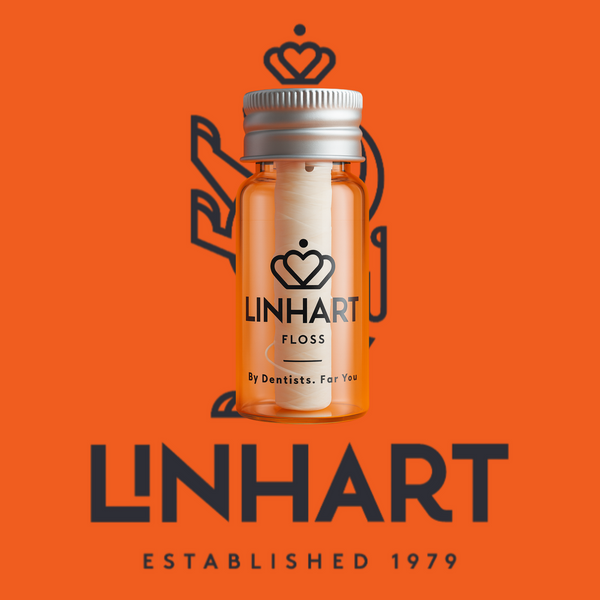 Clear small orange bottle with silver cap containing white microfiber dental floss, branded with "LINHART," set against an orange background with the text "LINHART Established 1979", showcasing Microfiber Floss | LINHART for oral wellness.
