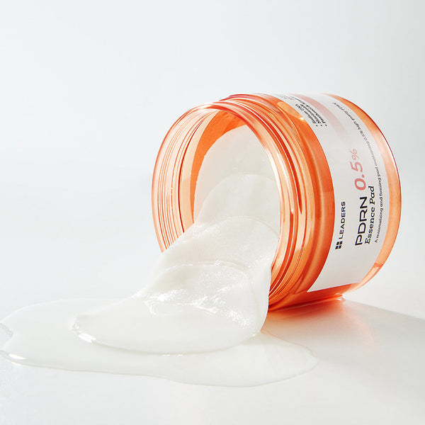 Open container of PDRN 0.5% Essence Pad | Leaders with white essence pads partially soaked in clear skincare essence spilling onto a smooth white surface.