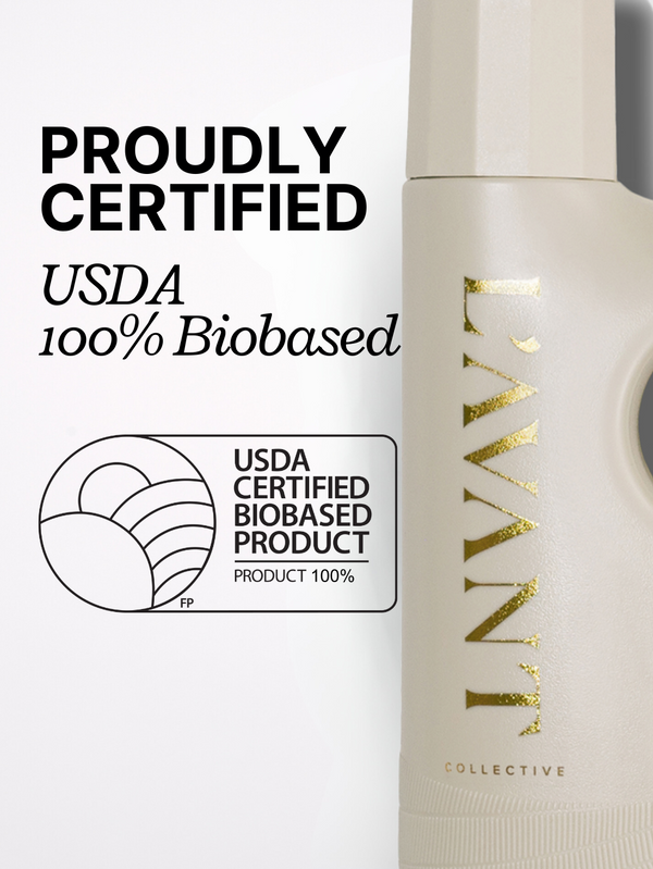Close-up of a beige laundry detergent bottle with gold "L'AVANT Collective" branding alongside a USDA 100% Biobased certification label and text stating proudly certified.