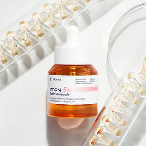 PDRN 5% Active Ampoule | Leaders skincare product with amber liquid in a clear bottle and white dropper, displayed alongside transparent vials on a white background.