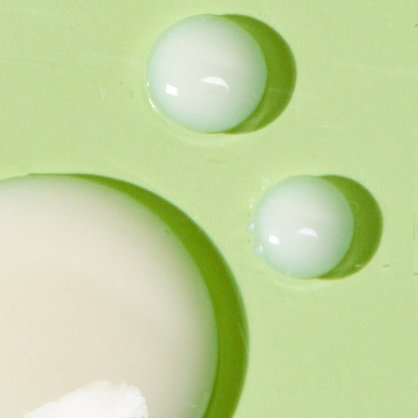 Close-up of creamy drops on a light green surface representing the texture of BIOME+ dew bright serum | IMAGE Skincare for nourishing skincare routines.