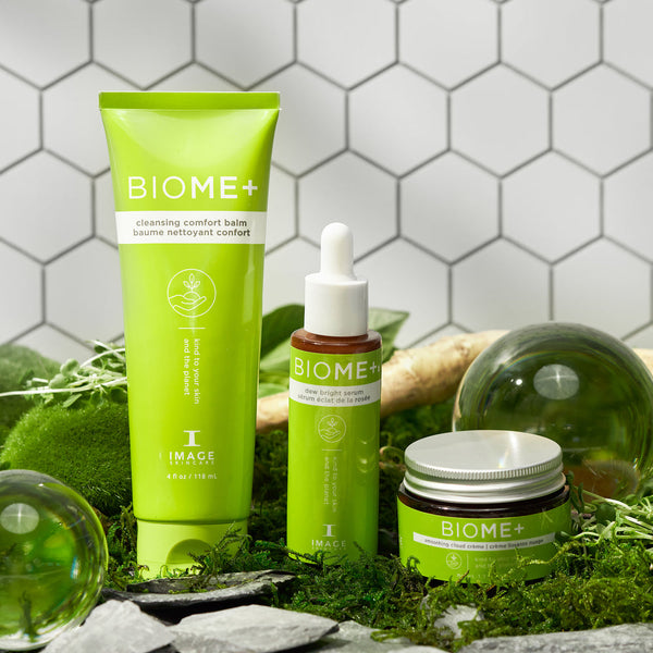 Three green BIOME+ skincare products from IMAGE Skincare displayed on moss and natural elements, highlighting the BIOME+ dew bright serum | IMAGE Skincare bottle with dropper.