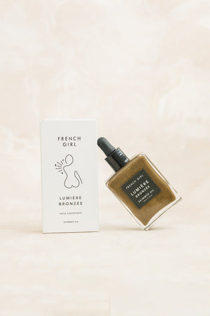 Bronzée Shimmer Oil| French Girl shimmering golden body oil with dropper bottle next to minimalist white packaging, ideal for skincare and body care routines.