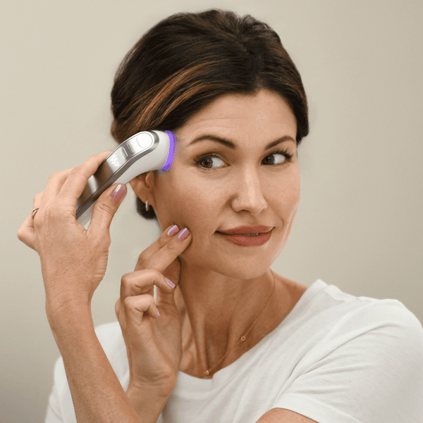 Woman using the C·A·R·A Multi-Modal Tool Kit | Althaea Skin on her face, demonstrating a wellness device for skincare and recovery treatments at home.