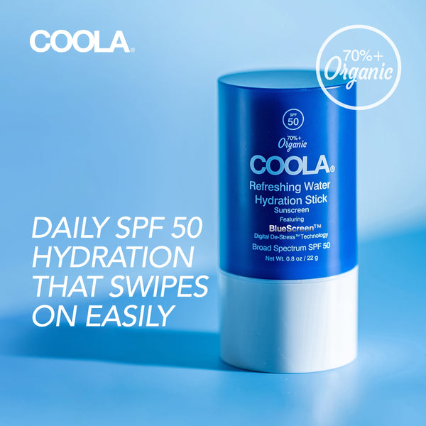 Blue and white container of Refreshing Water Stick SPF 50 | COOLA sunscreen with text highlighting daily hydration and 70% organic ingredients on a light blue background.