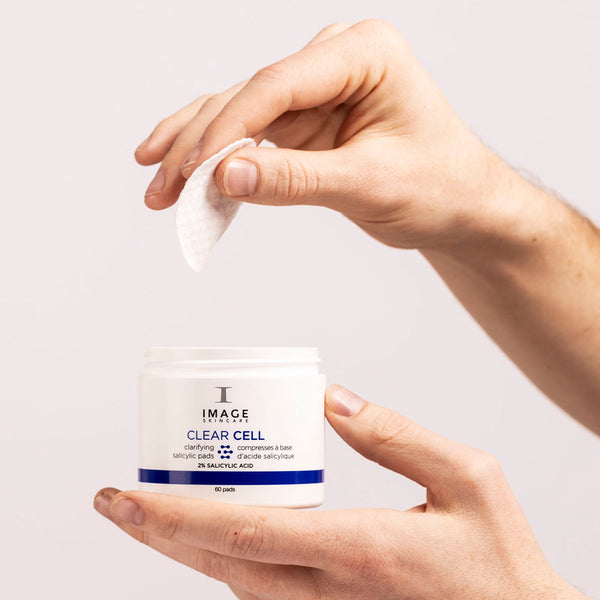 Hands holding a jar and a pad of CLEAR CELL salicylic clarifying pads | IMAGE Skincare, designed for skincare and skin clarity with salicylic acid.