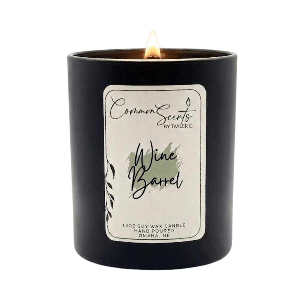 Lit Soft Crackling Wood Wick Candle | CommonScents in a sleek black container with a Wine Barrel scent label, showcasing a cozy and elegant ambiance for wellness and relaxation.
