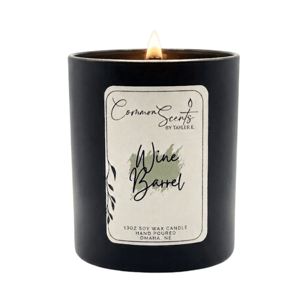Lit Soft Crackling Wood Wick Candle | CommonScents in a sleek black container with a Wine Barrel scent label, showcasing a cozy and elegant ambiance for wellness and relaxation.