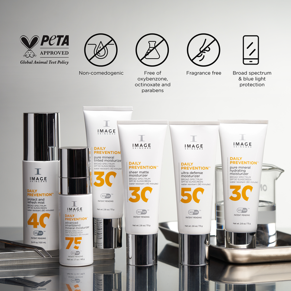 Array of IMAGE Skincare DAILY PREVENTION Ultra Defense Moisturizer SPF 50 and other SPF moisturizers displayed on reflective surface with icons indicating PETA approval, non-comedogenic, free of oxybenzone, octinoxate, parabens, fragrance-free, and broad spectrum with blue light protection.