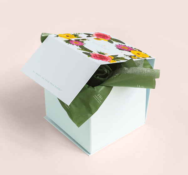 Elegant gift box with floral design lid partially open revealing green tissue paper, showcasing the Silky, Milky & Most Loved Naked Nourishment Set | Farmhouse Fresh skincare collection.
