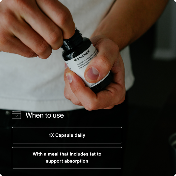 Person opening a bottle of supplements with text instructions for Vitamin D3 5000 IU recommending one capsule daily taken with a meal that includes fat to support absorption.