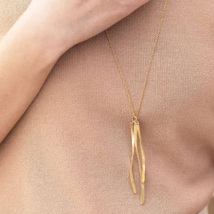Close-up of a person wearing a delicate gold necklace with two slender, textured pendants on a fine chain, showcasing the Kailani Necklace | Purpose Jewelry.