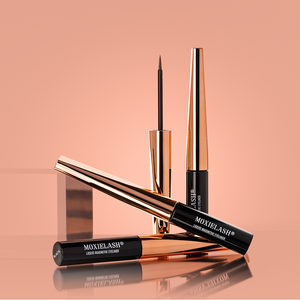 Three sleek black and rose gold tubes of Magnetic Liquid Eyeliner | Moxielash displayed against a soft peach background, with one open to reveal a fine precision brush.