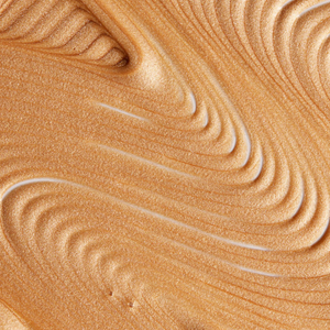 Close-up of a smooth, shimmering golden texture showing the luminous effect of Body Shimmer | NUDA, highlighting its radiant and glowing finish for skincare and body care.