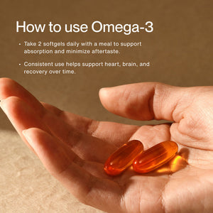 Hand holding two softgel capsules with text instructions on how to use Omega-3 Travel Packs for daily heart, brain, and recovery support by taking two softgels with a meal.