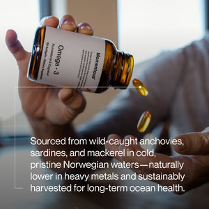 Person holding a bottle of Omega-3 supplements with soft gel capsules falling into an open hand, emphasizing natural wellness and high-quality ingredients.