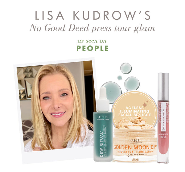 Image of a smiling woman with clear skin next to skincare products and Vitamin Glaze® Oil Infused Lip Gloss – Delicate Rose | Farmhouse Fresh in a soft pink shade.