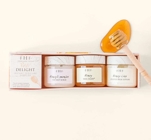 Set of three skincare jars including sea salt scrub, heel glaze, and milk lotion alongside a honey dipper with honey for the Fast Foot Revival Pedi Delight Sampler | Farmhouse Fresh.