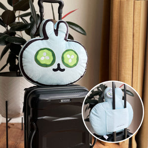 Spa Bunny Plushie | Lucky Owl in light blue with cucumber eye patches resting on black suitcase handle, with close-up of its back pocket holding suitcase handle for easy travel attachment.