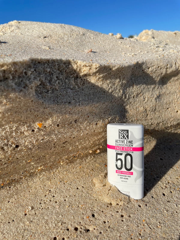 Zinc Sunscreen Stick for Face | SolRX Sunscreen placed upright on sandy beach with clear blue sky, highlighting SPF 50 skincare product for sun protection and wellness.