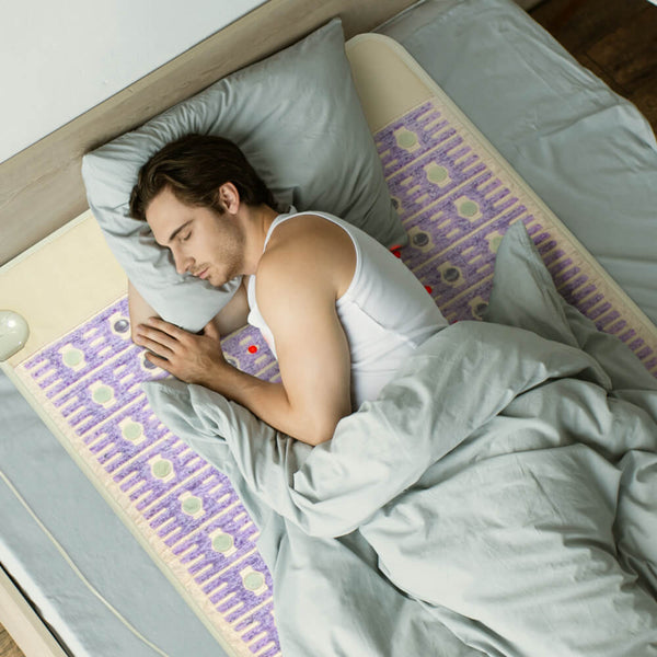 Man sleeping peacefully on a bed using the TAJ-Mat™ Full 7224 Firm - Photon PEMF InfraMat Pro® | HealthyLine wellness device designed for body care and recovery.
