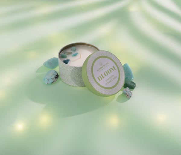 Bloom Candle Tin 6 oz | Aluminate Life with soothing stones inside on a soft green surface surrounded by natural light and shadows, evoking relaxation and wellness.