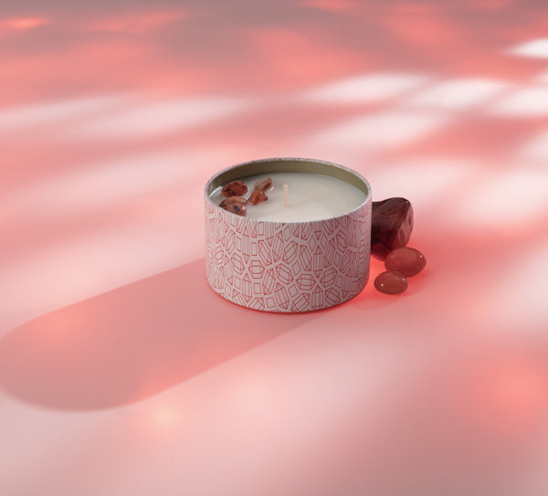 Energy Candle Tin 6 oz | Aluminate Life with decorative pink patterned container, small stones beside it on soft pink surface with gentle lighting, evoking relaxation and wellness.