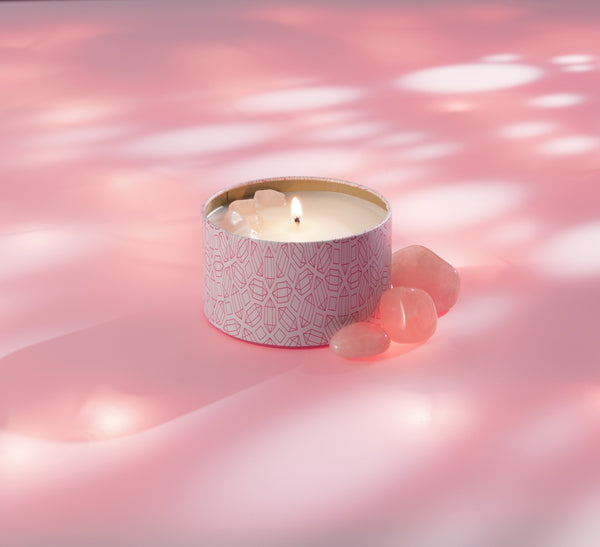 Lit Sleep Candle Tin 6 oz | Aluminate Life with decorative stones on soft pink surface, creating a calming wellness ambiance.