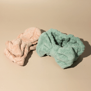 Two soft textured spa headbands in pastel peach and green colors displayed on a beige surface, designed for skincare and wellness use, Luxe Spa Headbands | Lucky Owl.