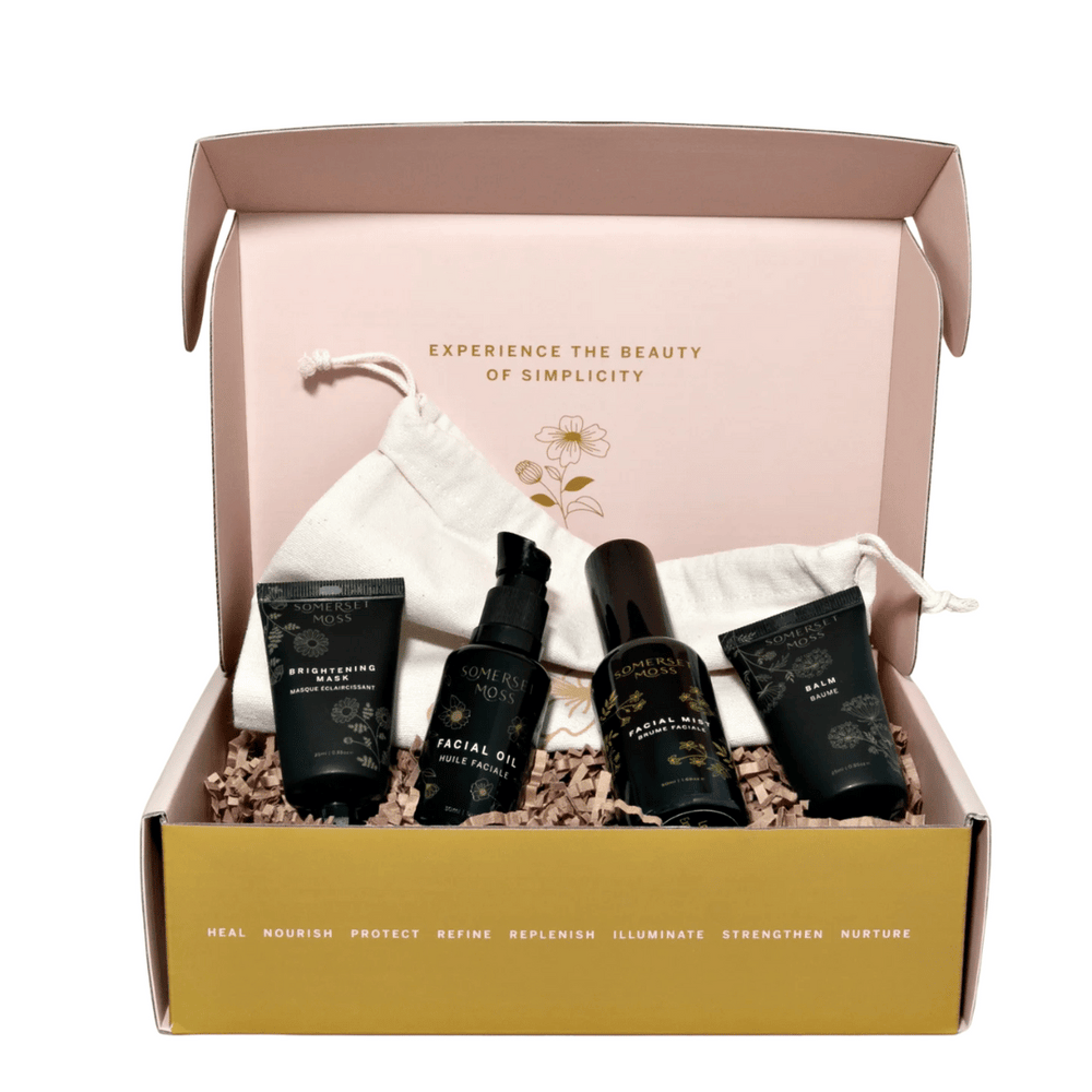 Open gift box displaying Discovery Kit | Somerset Moss skincare products, including tubes and bottles, with a soft drawstring pouch and a message inside the box about simplicity and wellness.