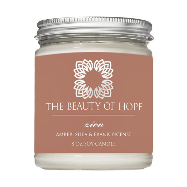 Zion 8oz Candle | The Beauty of Hope in a clear glass jar with a silver lid, featuring amber, shea, and frankincense scent for wellness and relaxation.