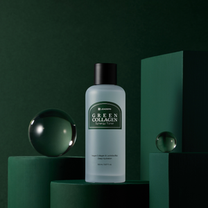 A bottle of Green Collagen Synergy Toner | Leaders displayed on dark green cylindrical and rectangular platforms with two clear glass spheres in the background, emphasizing skincare and hydration.