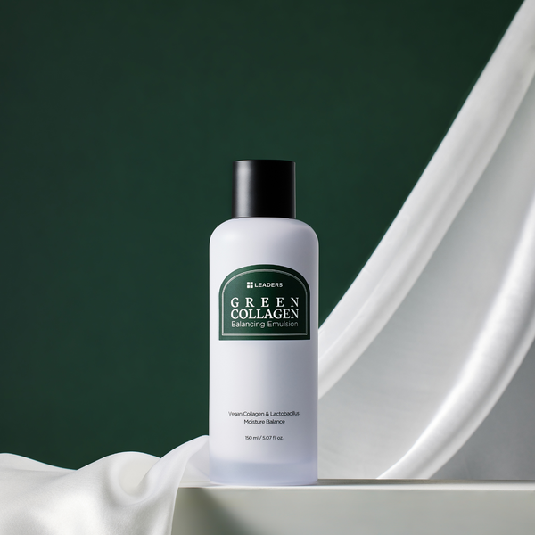 Bottle of Green Collagen Balancing Emulsion | Leaders placed on a white surface with soft white fabric and a dark green background, highlighting skincare and wellness.