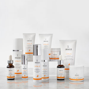 A collection of Image Skincare products arranged on a marble surface featuring VITAL C hydrating repair crème | IMAGE Skincare alongside other hydrating and skincare treatments in white and orange packaging.