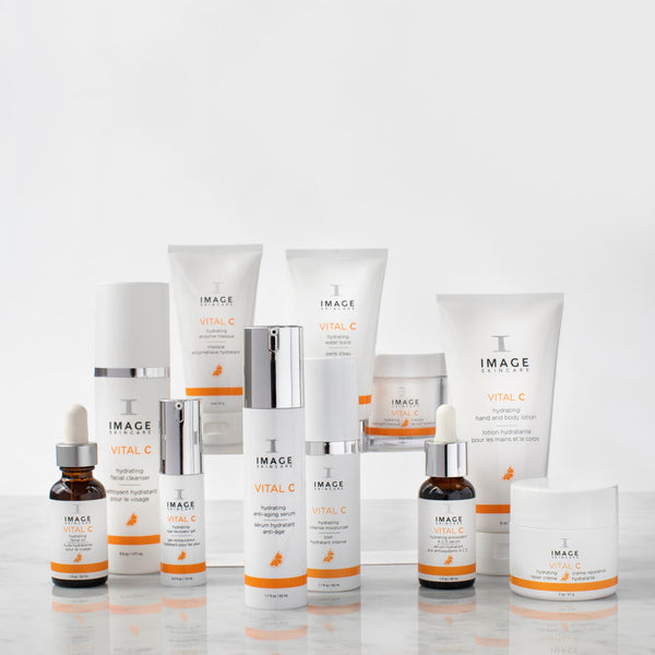 A collection of Image Skincare products arranged on a marble surface featuring VITAL C hydrating repair crème | IMAGE Skincare alongside other hydrating and skincare treatments in white and orange packaging.