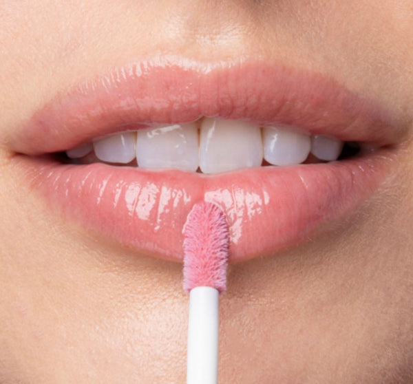 Close-up of lips with sheer pink gloss being applied using a soft applicator brush, showcasing Vitamin Glaze® Oil Infused Lip Gloss – Delicate Rose | Farmhouse Fresh for a natural, glossy finish.