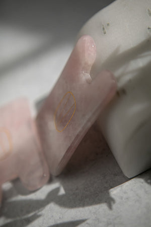 Close-up of a smooth, polished Rose Quartz Gua Sha | Vie Healing tool resting against a white marble surface, highlighting its soft pink hue and natural texture for skincare and wellness.