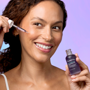 Woman applying Better With Age™ Renewing Bakuchiol Serum | ClarityRX to her cheek, showcasing skincare use and promoting healthy, glowing skin.