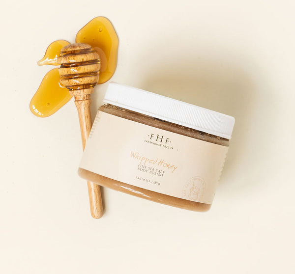 Jar of whipped honey body polish with wooden honey dipper and honey drizzled next to it, featuring Honey I’m Smooth Limited Edition Set | Farmhouse Fresh for skincare and body care.