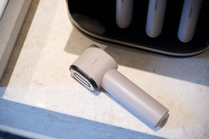 MediSpa Pro | Ceragem handheld wellness device designed for skincare and body care treatments, resting on a light-colored stone surface near its charging station.