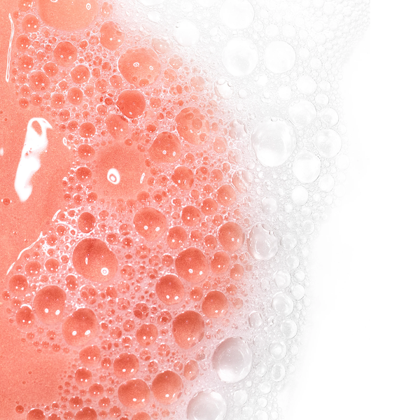 Close-up of foamy pink cleanser bubbles lathered on skin illustrating the cleansing action of AntiBlemish Cleanser | Skin Fitness Therapy for skincare and body care routines.