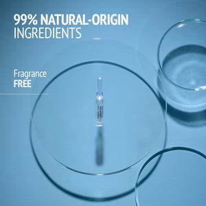 Single transparent ampoule placed in a petri dish on a blue surface, highlighting 99% natural-origin ingredients and fragrance-free features of Sublime Skin Lift & Firm Ampoules | [ comfort zone ].
