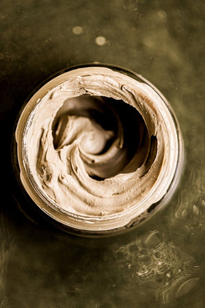 Open jar of creamy natural clay mask with smooth texture for skincare, showcasing Get Glowing Illuminating Clay Mask | VOYA for a radiant complexion.
