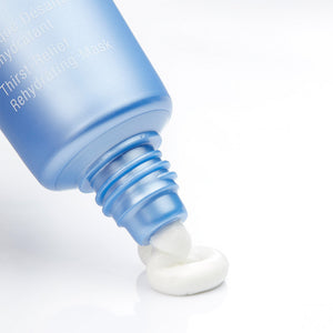 Close-up of a blue tube dispensing creamy white skincare product onto a smooth surface, showcasing Hydrasea Mask | Phytomer designed for hydration and skincare wellness.