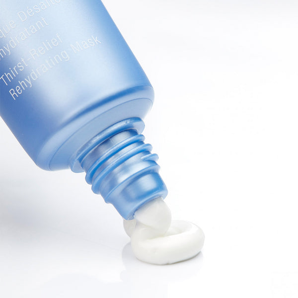 Close-up of a blue tube dispensing creamy white skincare product onto a smooth surface, showcasing Hydrasea Mask | Phytomer designed for hydration and skincare wellness.